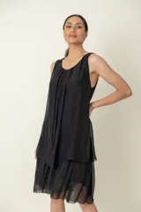 Vestido negro de seda, modelo suelto sin mangas, con escote redondo y volados en el bajo.