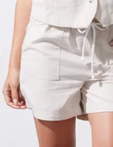 Short color crema con finas rayas verticales grises, pretina elastizada con cordón de ajuste, bolsillos delanteros y traseros.