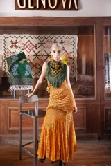 Falda larga de encaje de terciopelo color mostaza, con diseño de caderín en picos, volados decorativos y corte evasé con terminación irregular.
