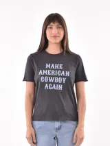 Remera gris oscuro con estampa frontal con la frase "Make American Cowboy Again" en letras celestes.