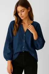 Camisa azul oscuro de algodón con cuello mao y escote en V con botones. Presenta mangas largas abullonadas con puños fruncidos y bordados florales tonales en los hombros.