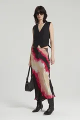 Falda midi de viscosa estampada con diseño abstracto en tonos beige, rosa y negro. Corte al bies con ruedo acampanado y cierre lateral invisible.