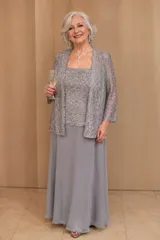 Vestido largo de fiesta compuesto por un top de encaje bordado con lentejuelas, una falda de gasa fluida y una chaqueta de encaje a juego con mangas tres cuartos.