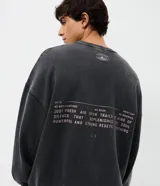 Buzo de cuello redondo y manga larga, con calce oversized y acabado lavado. Presenta estampado frontal con diseño gráfico y texto 'Silence Everything'. Confeccionado en frisa de algodón y poliéster.