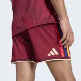 Short de fútbol Adidas, versión Fan, color granate (similar al rojo oscuro), con detalles en amarillo en los bordes. Presenta el escudo de la Federación Venezolana de Fútbol (FVF) bordado en el muslo izquierdo.