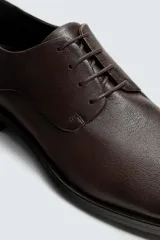 Zapato de vestir tipo derby, color negro, fabricado en piel con horma cuadrada y suela con ligero tacón.