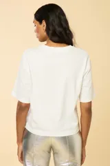 Remera blanca de corte holgado con mangas cortas acampanadas, cuello redondo y apliques de strass con forma de conchas en el frente.