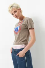 Remera corta color marrón con estampa frontal de escudo deportivo con la leyenda "Sports League" y el año 1991.