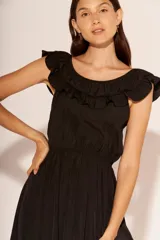 Vestido corto de color negro, con escote redondo adornado con volados y cintura elástica.