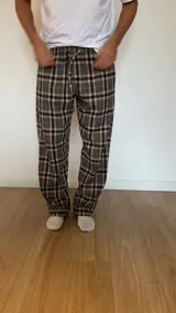 Pantalón de hombre confeccionado en franela. Diseño escocés a cuadros grises, beige y negros, con elástico en la cintura y dos bolsillos laterales.