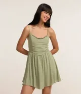 Enterito corto de viscosa color verde oliva, con breteles finos, escote con detalle de volados y corte entallado en la cintura con falda acampanada.