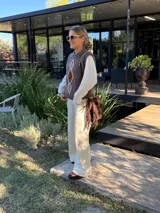 Chaleco tejido de punto en color chocolate, con cuello redondo y diseño sin mangas. Presenta un aplique frontal decorativo compuesto por tres figuras en forma de rombo en tonos tierra, bordeadas con hilo crudo.