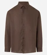 Camisa de corte relajado confeccionada en cambraia de lino puro. Presenta cuello inglés, cierre frontal con botones y mangas largas.