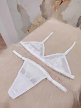 Conjunto de lencería compuesto por un corpiño triangular de microtul transparente con detalles de encaje floral y una tanga regulable a juego.