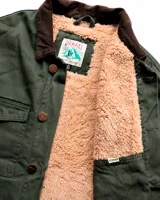 Campera estilo workwear de canvas resistente color verde oscuro. Cuenta con interior forrado en corderito sherpa, cuello de pana en tono marrón, cierre frontal con botones metálicos color cobre, cuatro bolsillos frontales y un bolsillo interior.