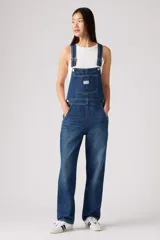 Overall de jean en color azul clásico con lavado desgastado. Presenta un diseño de corte recto y holgado, con bolsillo frontal en el pecho, tirantes ajustables con hebillas metálicas y bolsillos laterales.