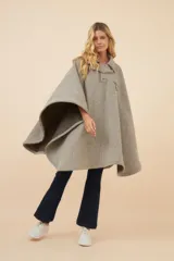 Poncho de lana fina con diseño de rayas diagonales, cuello camisero, cartera con botones a presión y bolsillo ojal en el pecho.
