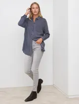 Camisa de corte largo y holgado, con estampado de rayas verticales en azul marino y blanco. Presenta cuello con solapa, cierre frontal con botones, bolsillo en el pecho y mangas largas con puños abotonados.