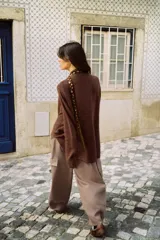 Jersey de punto color marrón con cuello subido y manga larga. Presenta un diseño de cuerpo amplio estilo capa con sisa ancha y bajo asimétrico con aberturas laterales.