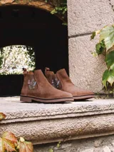 Botin de cuero serraje color beige, con elastico lateral decorado con bordado floral multicolor y suela baja de goma.