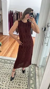 Vestido midi de punto sin mangas, color bordó con destellos de lurex. Presenta un diseño de rombos en la parte superior y una textura de red en la parte inferior, con tajos laterales en el ruedo.