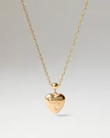 Dije en forma de corazón de metal dorado con la inscripción "mom" grabada y dos circonias incrustadas.