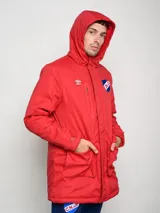 Parka larga de abrigo color azul marino, con capucha, cierre frontal, bolsillos con solapa y bolsillo superior con cierre. Presenta el logo de Umbro y el escudo del Club Nacional de Football.