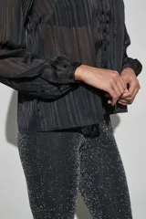 Blusa negra de tela semitransparente con diseño de rayas verticales texturizadas, cuello con volados y cierre frontal de botones.
