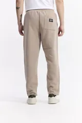 Pantalón de jogging color beige, confeccionado en algodón y poliéster, con cintura elástica y cordón ajustable. Diseño clásico sin puño en los tobillos.