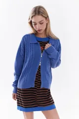 Sweater tejido de punto color azul, con cierre frontal de doble cursor y efecto desgastado. Presenta mangas largas, cuello tipo polo y detalles de trenzas en el tejido delantero.