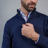 Buzo de punto color beige con cuello alto y medio cierre frontal.