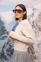 Buzo de punto grueso en color beige, con diseño de trenzas verticales y cuello redondo.