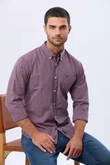 Camisa de manga larga con estampado de cuadros pequeños en tonos rojo, azul y blanco. Presenta cuello abotonado, cierre frontal con botones y un bolsillo pequeño en el pecho.