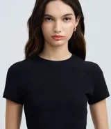 Blusa femenina de corte cropped, color verde oliva, con cuello redondo y mangas cortas. Confeccionada en algodón con elastano, ofrece un ajuste cómodo y versátil.