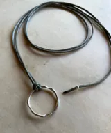 Gargantilla con cordón gris y dije circular de plata.
