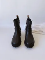 Bota corta negra de cuero, con caña media, hebilla lateral y suela track.