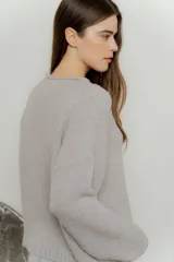 Sweater de punto con textura suave, color gris, de corte holgado, cuello redondo con terminación rulé y mangas largas con puños acanalados.