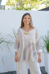 Sweater de punto con diseño de ondas en tonos beige y gris, de corte amplio, escote en V y mangas largas con puños vueltos.