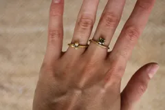 Anillo dorado con una gema verde cuadrada.