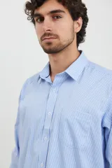 Camisa celeste con rayas verticales blancas, de manga larga con puños abotonados y cuello clásico.