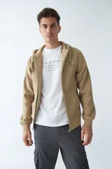 Campera de felpa color blanco hueso, con capucha y cordón ajustable, cierre frontal con cremallera, bolsillos laterales, logo y arte estampado en el pecho.