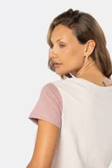 Remera de manga corta con cuello redondo y diseño de bloques de color. El cuerpo es beige, la manga izquierda es azul claro y la manga derecha es rosada.