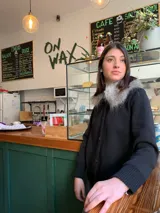 Cárdigan negro de lana merino con cuello de piel sintética gris. Tiene cierre frontal con botones.