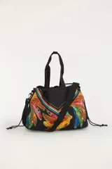 Bolso amplio tipo shopper color negro, con estampado tropical colorido de bananas y detalles geométricos. Cuenta con asas superiores y correa ajustable para el hombro.