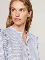 Blusa celeste a rayas verticales, de corte amplio, con cuello mao, cierre de botones y volantes en los hombros.