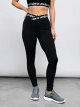 Calza deportiva Umbro modelo Legging Bink para mujer, de color negro, con cintura alta cruzada y elástica con la marca estampada.