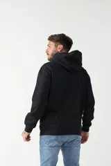 Buzo canguro negro con capucha ajustable y bolsillo frontal. Presenta un estampado gráfico en el pecho con texto y líneas decorativas, además de un detalle estampado en la manga.