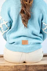 Cárdigan celeste de lana merino con diseño calado en color crudo y botones de nácar.
