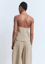 Chaleco tipo halter de color tostado, con escote pronunciado, cierre frontal de botones y bolsillos de solapa laterales.