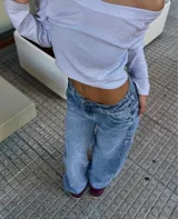 Jean de tiro bajo con corte wide leg y diseño de cinco bolsillos. Presenta un lavado clásico en tono azul medio con efecto desgastado.